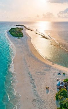 an aerial view of the beach and ocean with boats on it's shore at sunset