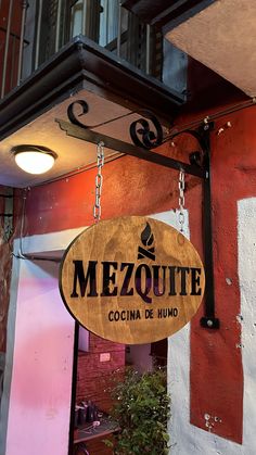 a sign hanging from the side of a building that says mezquite in spanish