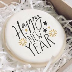 a happy new year cookie in a gift box with white ribbon and black lettering on it