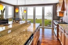 a kitchen with granite counter tops and an island in front of a large window overlooking the ocean