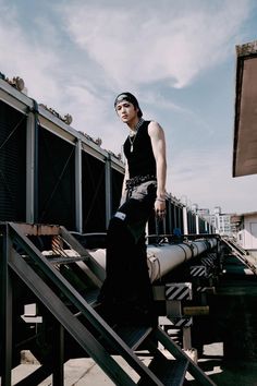 a woman standing on top of a metal stair case next to a bunch of pipes