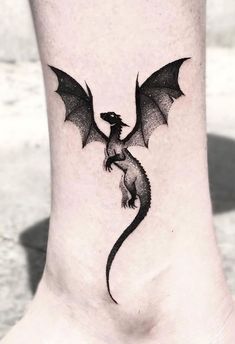 a small black dragon tattoo on the foot