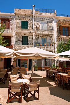 an outdoor dining area with tables and umbrellas in front of a building that has balconies on it