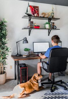 a young boy sitting at a desk with his dog on the floor next to him