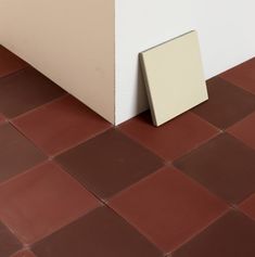 the corner of a room with red and white tiles on the floor next to it