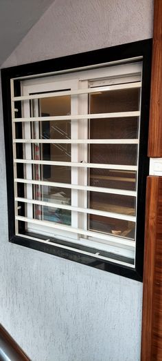 a window with blinds on the side of it in front of a wall and stairs