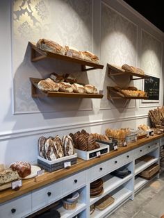 breads and pastries are displayed on shelves in the bakery's display area