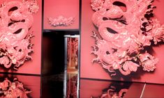 a pink wall with two dragon masks on it