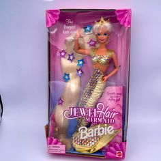 a barbie doll with blonde hair and gold outfit in a box next to a pair of sunglasses