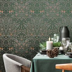 a dining room table is set with place settings for two, and the wall paper has floral designs on it