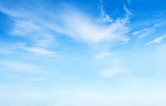 two people walking on the beach with surfboards under a blue sky and white clouds