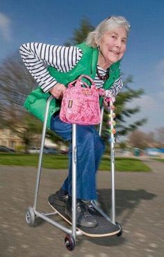 an older woman riding a scooter with a pink purse on it