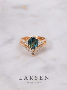 a green and white diamond ring on top of a marble surface with the words, lauren jewelry