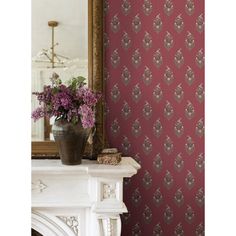 a vase filled with purple flowers sitting on top of a white mantle next to a mirror