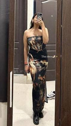 a woman taking a selfie in front of a mirror wearing a black and gold dress