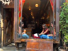 three people sitting on a bench in front of a store with lots of open windows