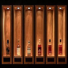 four bottles of alcohol are lined up in a wooden case with lights on the sides