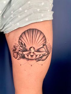 a woman's thigh with a shell tattoo on it