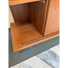 a close up of a wooden cabinet on carpeted floor next to wall and door