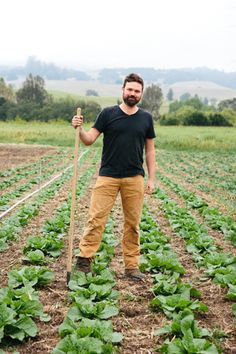 a man standing in a field holding a stick