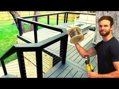 a man holding a sanding disc on top of a wooden deck next to a tree