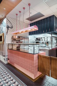 the interior of a restaurant with pink and black tiles on the floor, lights hanging from the ceiling