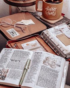 an open book sitting on top of a wooden table next to a cup of coffee