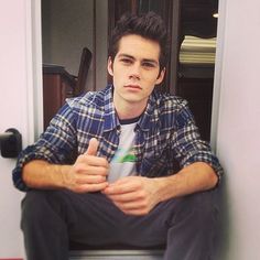 a young man sitting on the floor in front of a door with his hands crossed