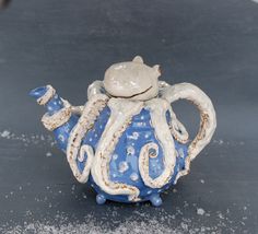 a blue and white ceramic teapot with an octopus on it's side sitting on a table