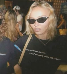 a woman with sunglasses on her head is standing in front of other people wearing black t - shirts