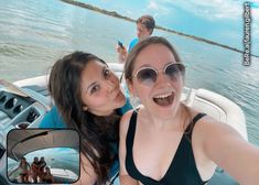 two women taking a selfie on a boat in the water with other people behind them