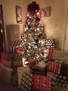 a christmas tree with presents under it and lights on the top is surrounded by other wrapped gifts