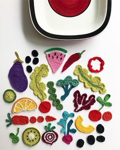 crocheted fruits and vegetables on a plate next to a bowl with a fork