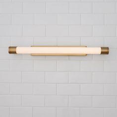 a white brick wall with a gold colored light fixture on it's left side