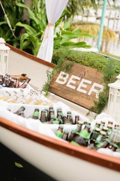 a boat filled with beer bottles sitting on top of a lush green field next to a sign that says beer