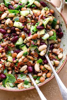 a bowl filled with beans, cucumbers and other vegetables on top of a table