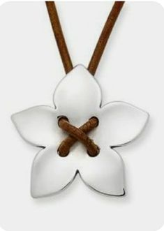 a white flower with two wooden sticks in it's center on a leather cord