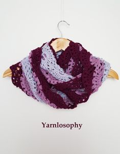 a crocheted shawl hanging on a wooden hanger with the word yarn photography written below it