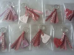 six heart shaped keychains in plastic bags on a white tablecloth with red and white ribbons