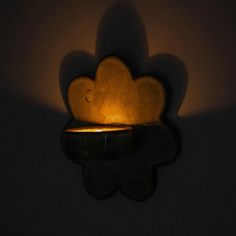 a candle that is lit up in the dark with its shadow on the wall behind it