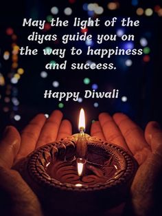 someone holding a lit candle in their hands with the words happy diwali on it