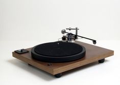 an old record player sitting on top of a wooden table with a white wall in the background