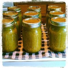 several jars filled with green liquid sitting on top of a checkered table cloth next to each other