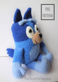 a blue crocheted stuffed animal sitting next to a white wall