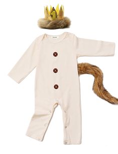 a white baby romper with a brown fox tail and a gold crown on top