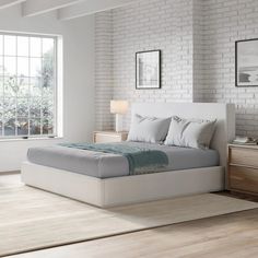 a white bed sitting next to a window in a bedroom on top of a hard wood floor