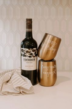 a bottle of booze next to two glasses and a towel on a counter top