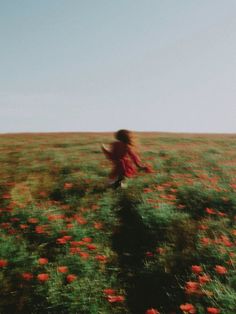 a girl running through a field full of red flowers