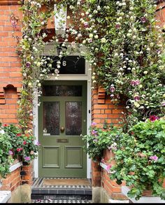 a green door surrounded by plants and flowers