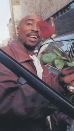 a man holding a rose in his hand while sitting in the back of a car